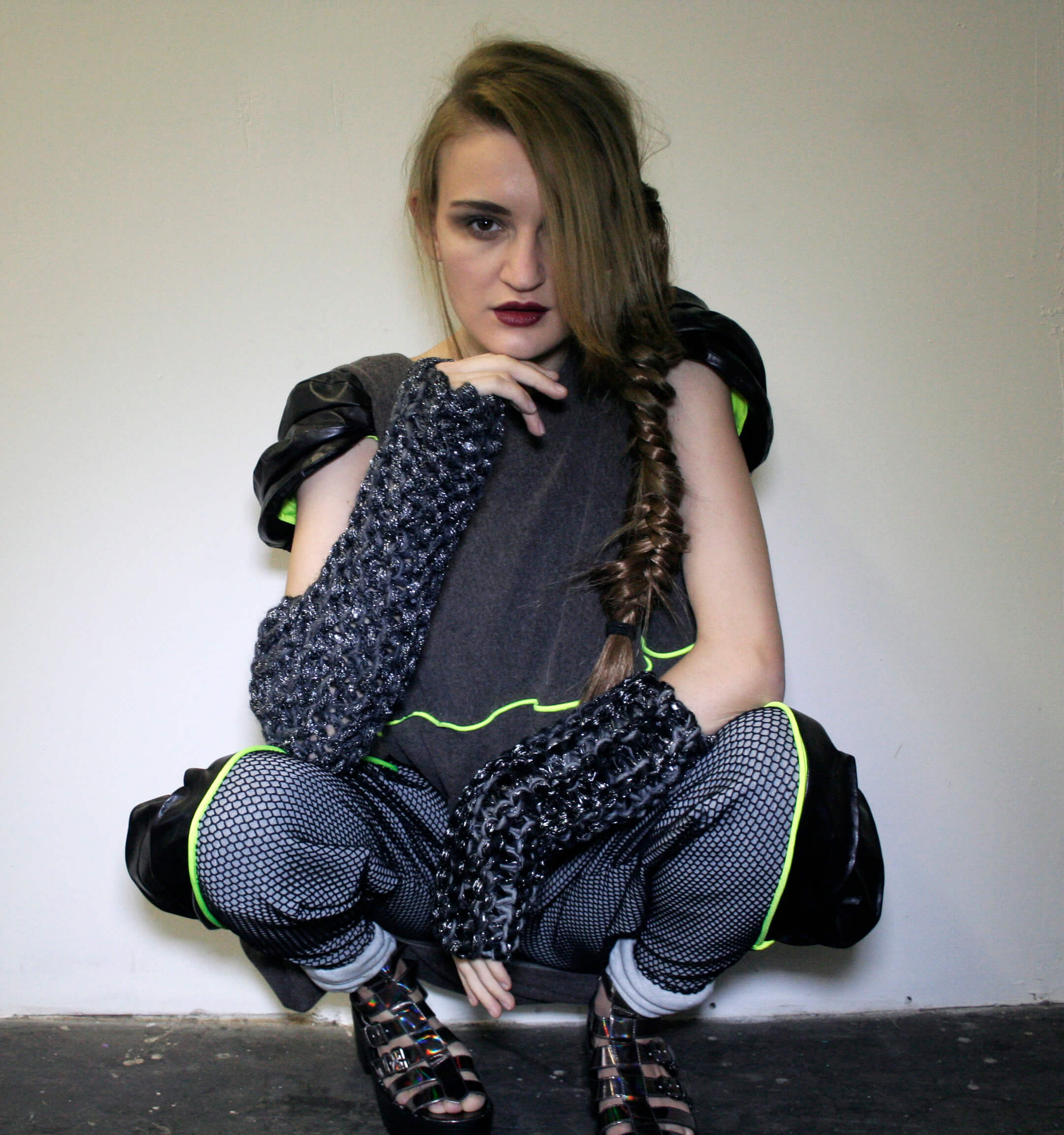 Photoshoot from the Armatura collection showing a balloon-style top with sculpted leather cap sleeves, paired with fishnet-paneled leggings and pleated leather side inserts