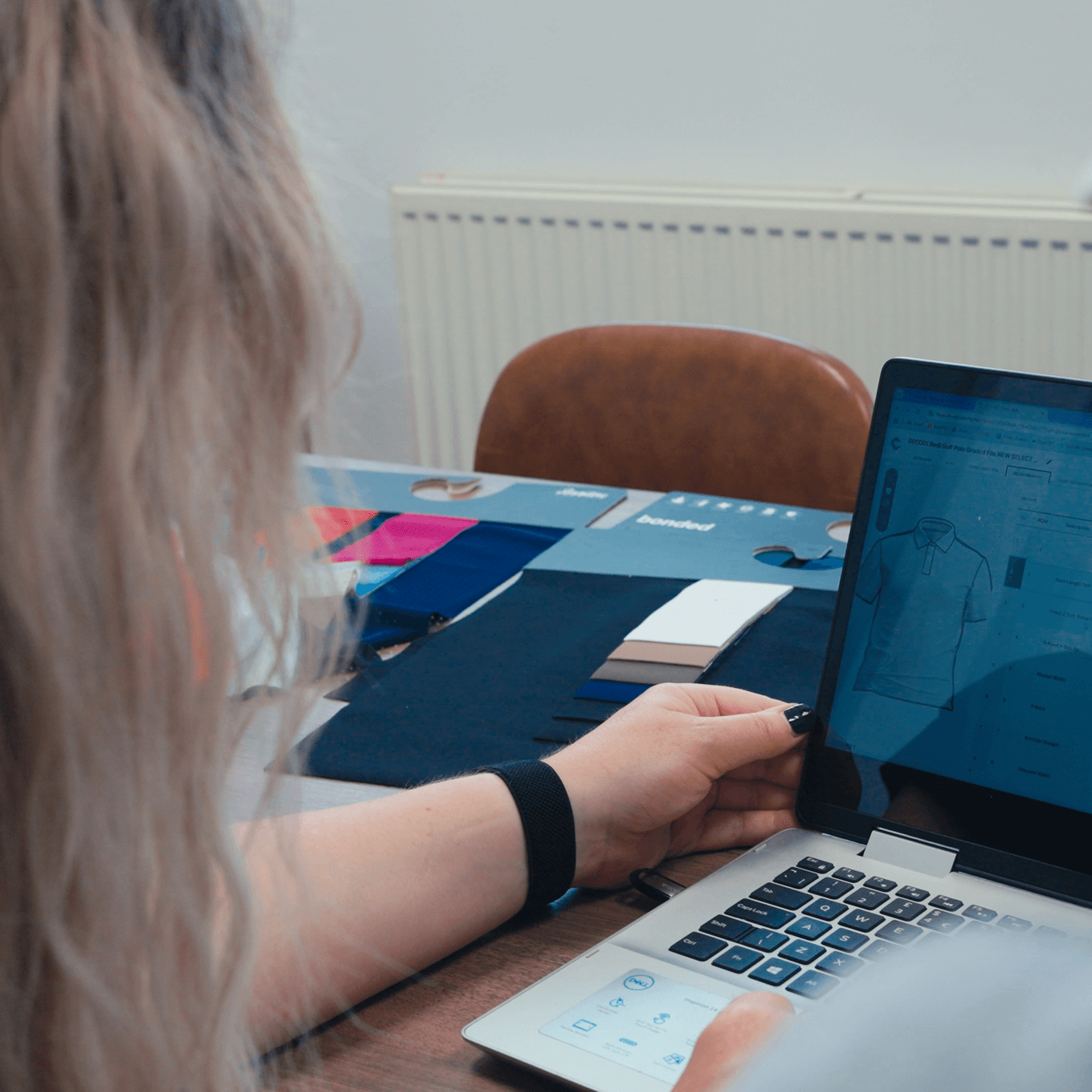 Laura from Fashion Toolbox reviewing 3D garment designs with a client on a laptop, surrounded by fabric swatches and sample books during a design consultation session