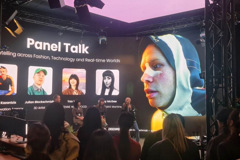 Panel talk on fashion, technology and real-time worlds, with speakers on stage and a large digital character image on the screen behind them.